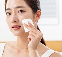 여성이 화장솜으로 볼을 닦는 모습