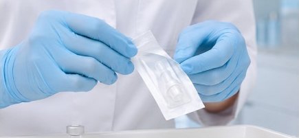 파란 장갑을 낀 손이 개별 포장된 일회용 시술 팁을 개봉하는 모습