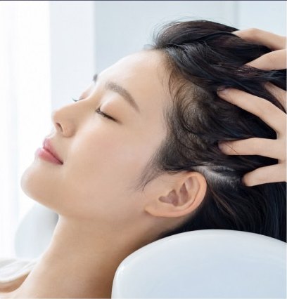 샴푸대에 기대 눈을 감은 여성의 두피를 손가락으로 마사지하는 장면